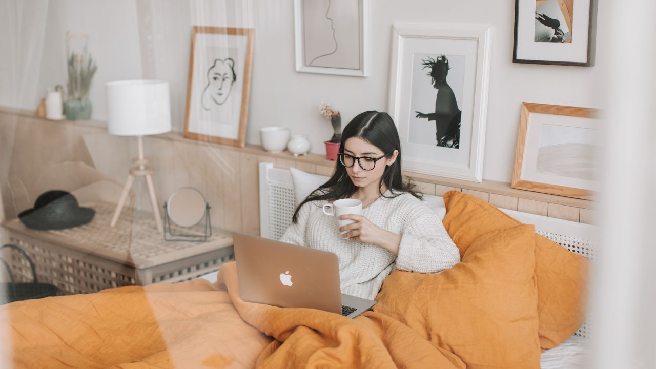 A Girl Blogging while drinking coffee in bed.